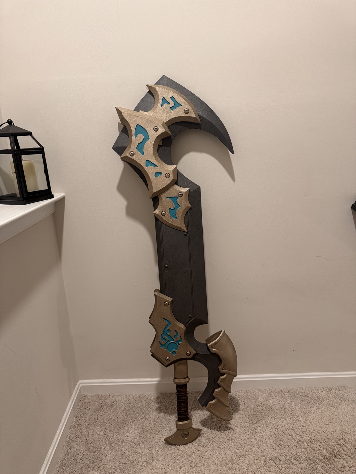 Large black-and-gold WARMACHINE Warcaster Weapon with turquoise accents leaning against a wall
