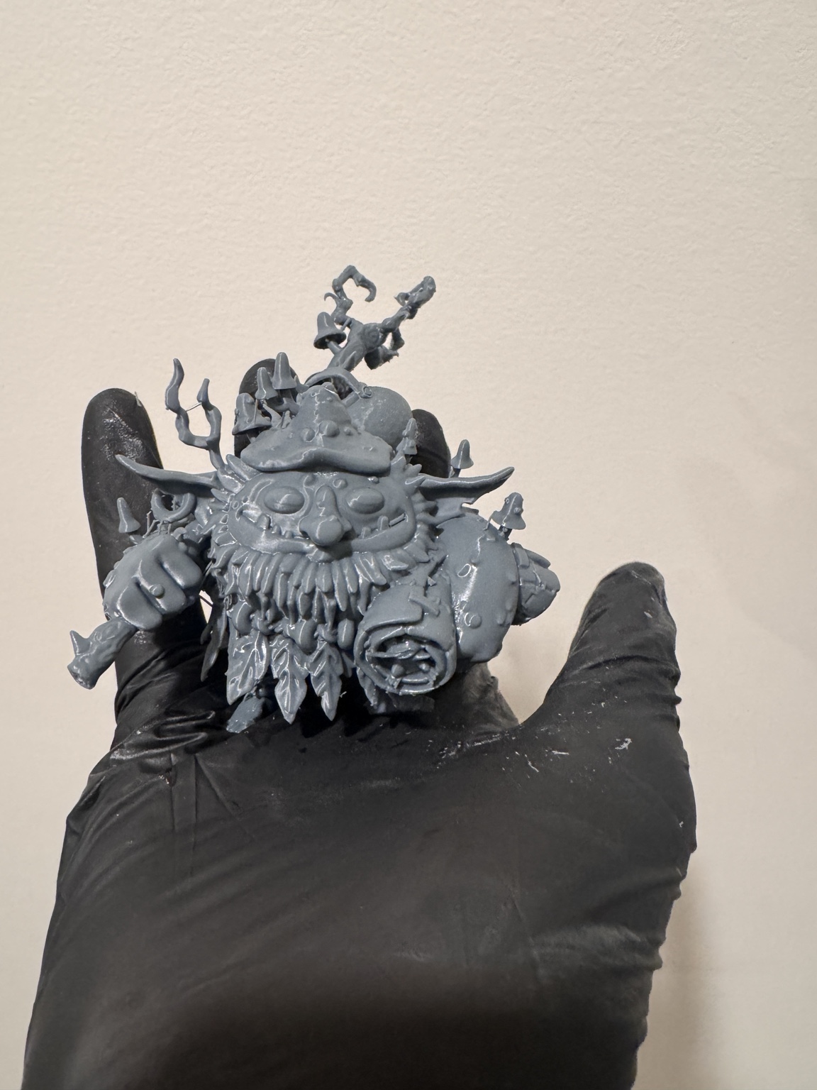Group of unpainted mushroom-themed miniatures held in a gloved hand